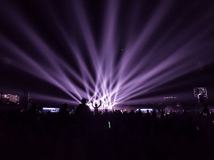 A lively night concert with beams of colorful lights and an energetic crowd